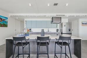 A modern kitchen with a central island, bar stools, and a large window. - NEW Harbour Nine at The Wharf Urban Elegance (Willemstad)