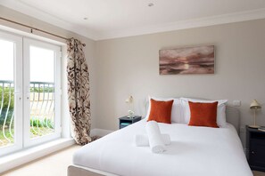 A bedroom with a large bed, a painting on the wall, and a view of the outdoors through a window. - Spacious Sidlesham Country Home Near Witterings (Chichester)