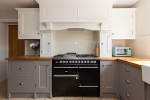Eine Küche mit Gasherd, Backofen und einer Retro-Mikrowelle.