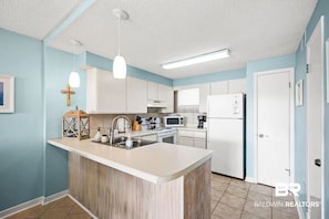 Una cocina moderna con armarios blancos, una isla central y un microondas.