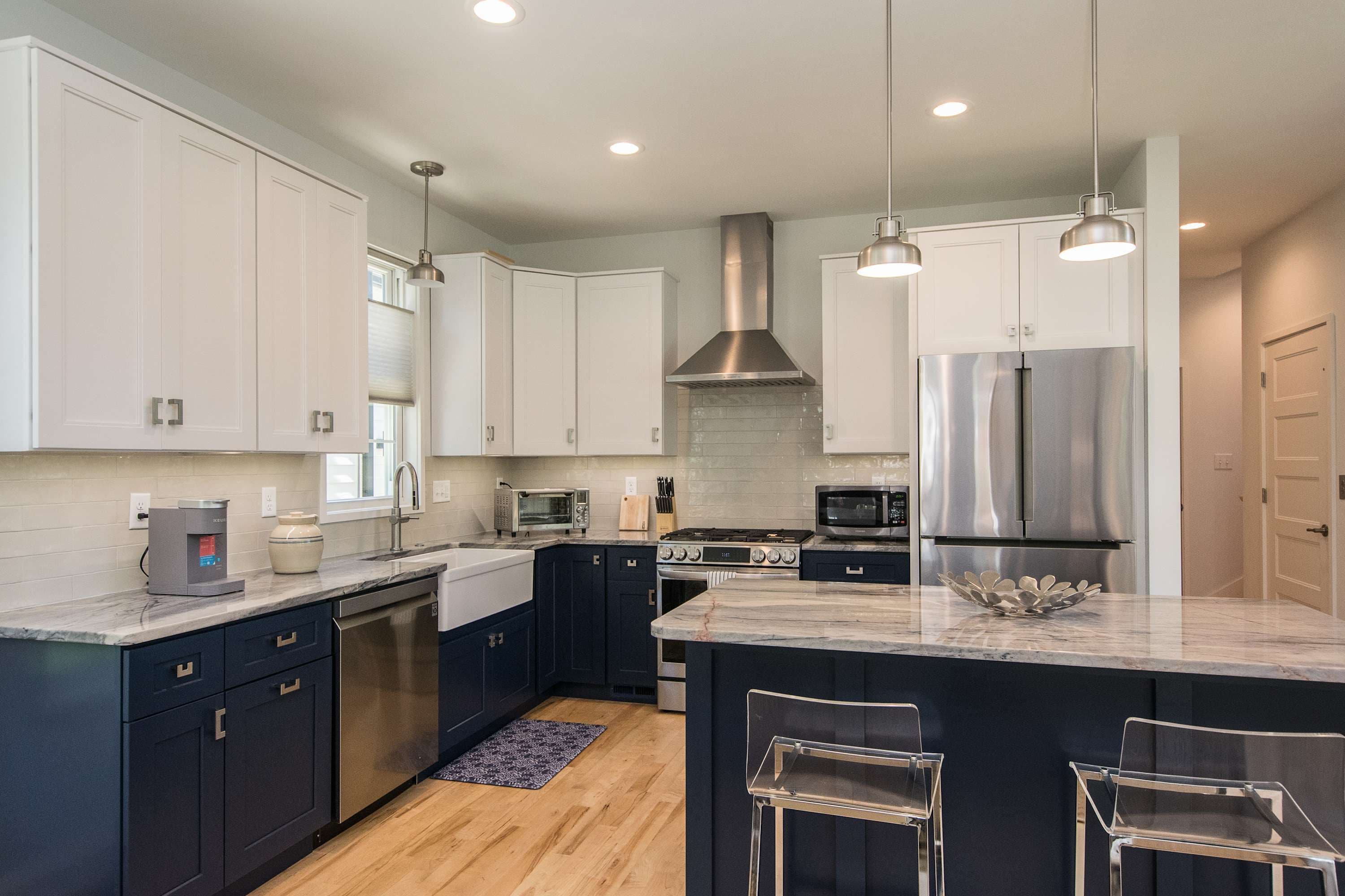 A modern kitchen with dark cabinetry, stainless steel appliances, and pendant lighting.