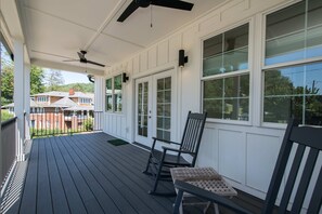 A covered porch with a wooden floor, two ceiling fans, and a bench. - 2BR Saluda Townhome Elevator Free Tix (Saluda)