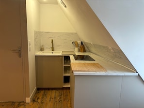 A compact kitchen with a built-in sink, a wooden countertop, and a marble backsplash. - Le Grenier Chic Duplex Cosy Dans le Vieux Arras (Arras)