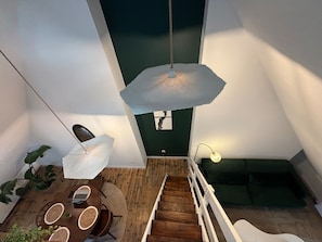 A modern interior with a staircase, a dining area, and a green sofa. - Le Grenier Chic Duplex Cosy Dans le Vieux Arras (Arras)