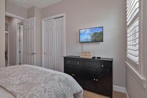 A bedroom with a bed, a dresser, a television on the wall, and a door. - Sunny Lakeview Pool & Spa Retreat in South Fort Myers (Fort Myers)