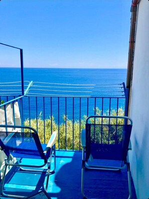 Ein Balkon mit zwei Stühlen, einem Geländer und Blick aufs Meer.