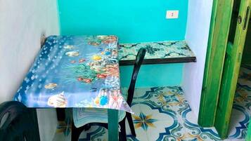 A small room with a table and chairs, a window, and patterned floor tiles.