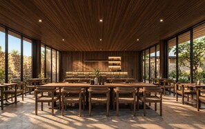 Un comedor amplio con una larga mesa de madera rodeada de sillas, ventanas grandes y una pared de piedra de fondo.