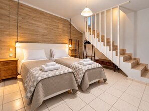 Ein modernes Schlafzimmer mit zwei Betten, einer Holzwand, einer Treppe und einer Pendelleuchte.