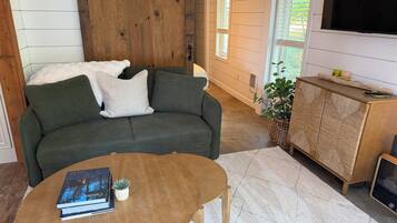 A cozy living room with a green sofa, a wooden coffee table, and a cabinet with a woven design.