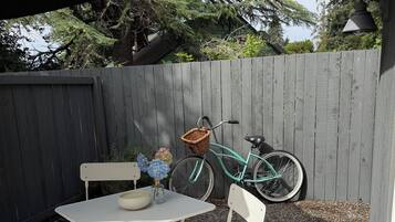 A patio with a white table and chairs, a wicker basket, and a bicycle.