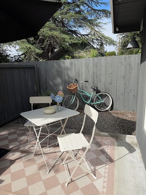 A patio with a white table and chairs, a wicker basket, and a bicycle.