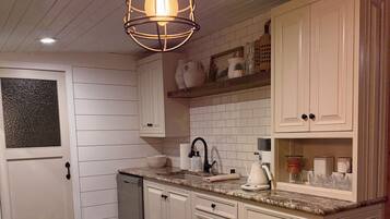 A kitchen with white cabinets, a wooden table, and a hanging light fixture.