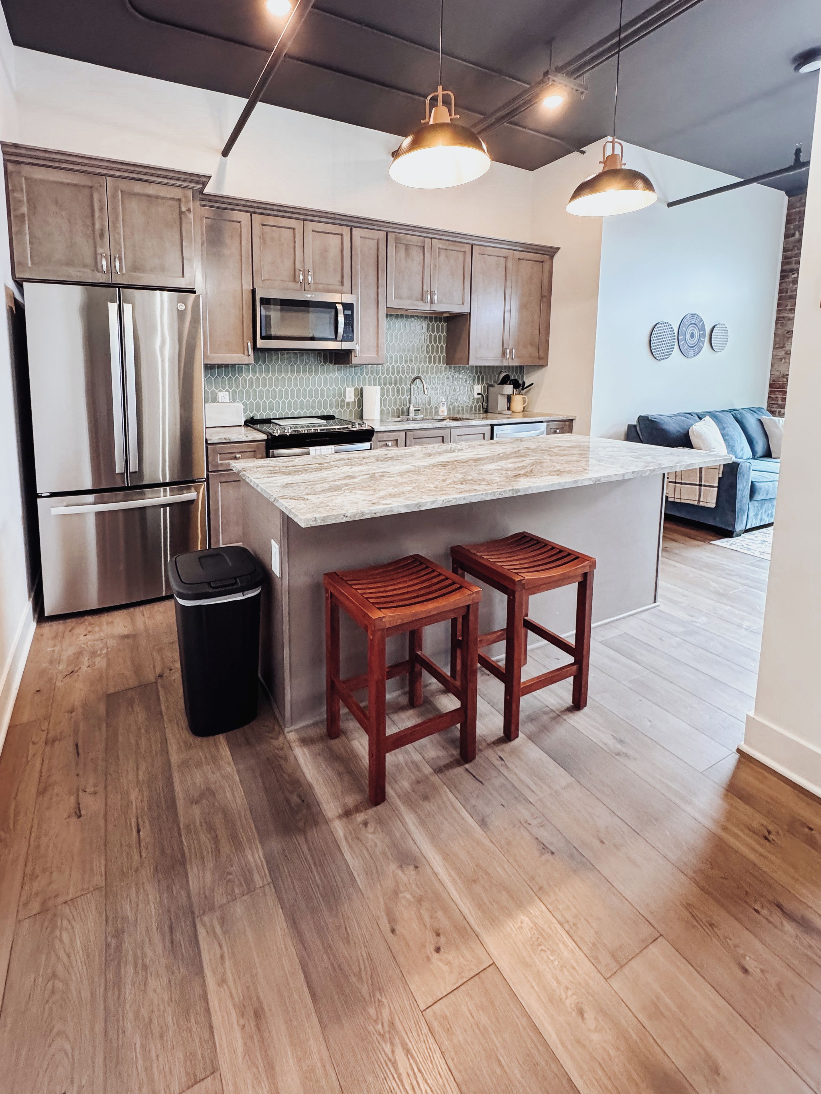 Una cocina moderna con electrodomésticos de acero inoxidable, taburetes de madera y una isla grande.