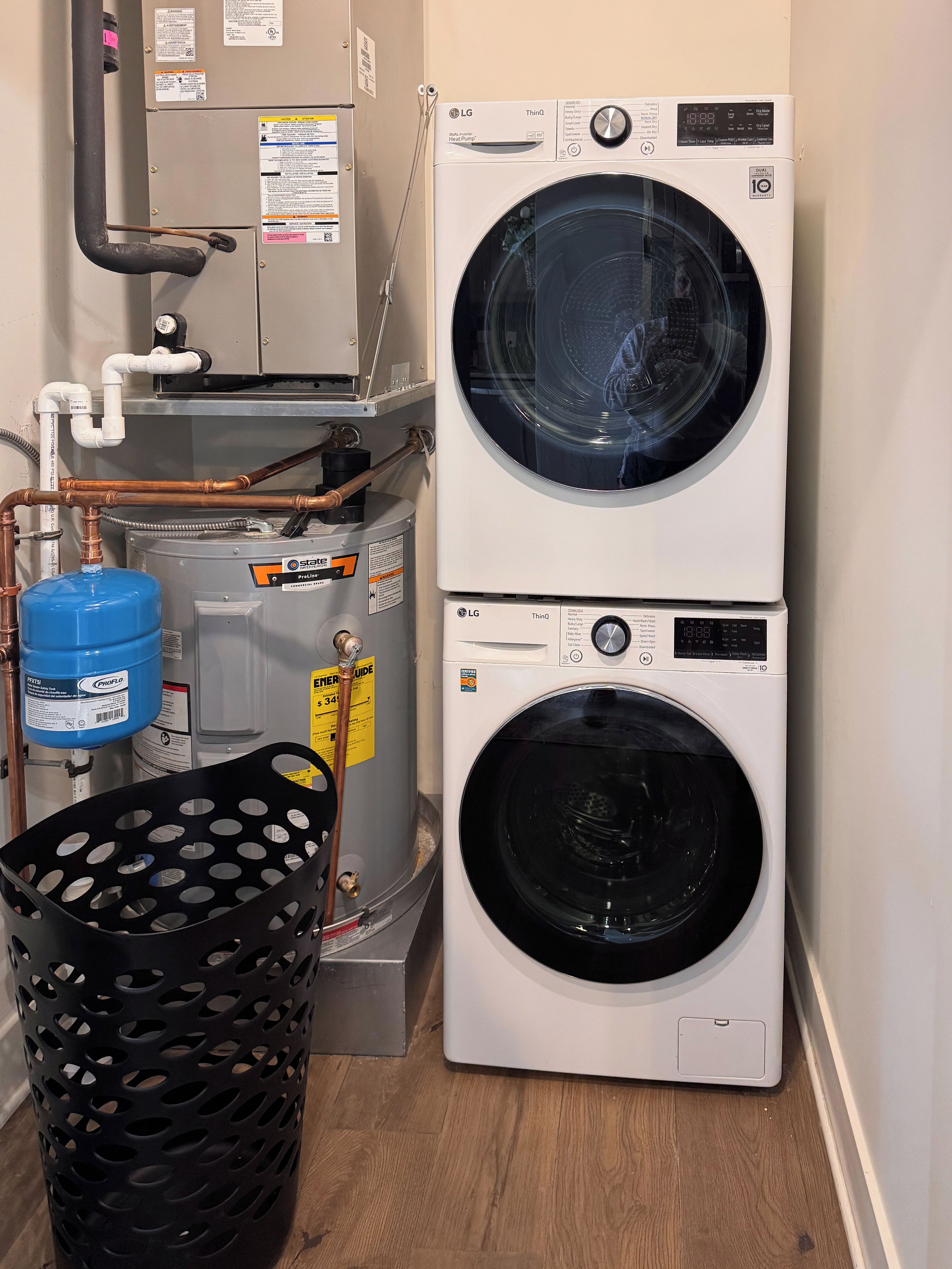 A laundry area with two stacked washing machines, a water heater, and a water storage tank.