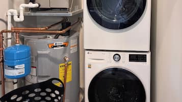 A laundry area with two stacked washing machines, a water heater, and a water storage tank.