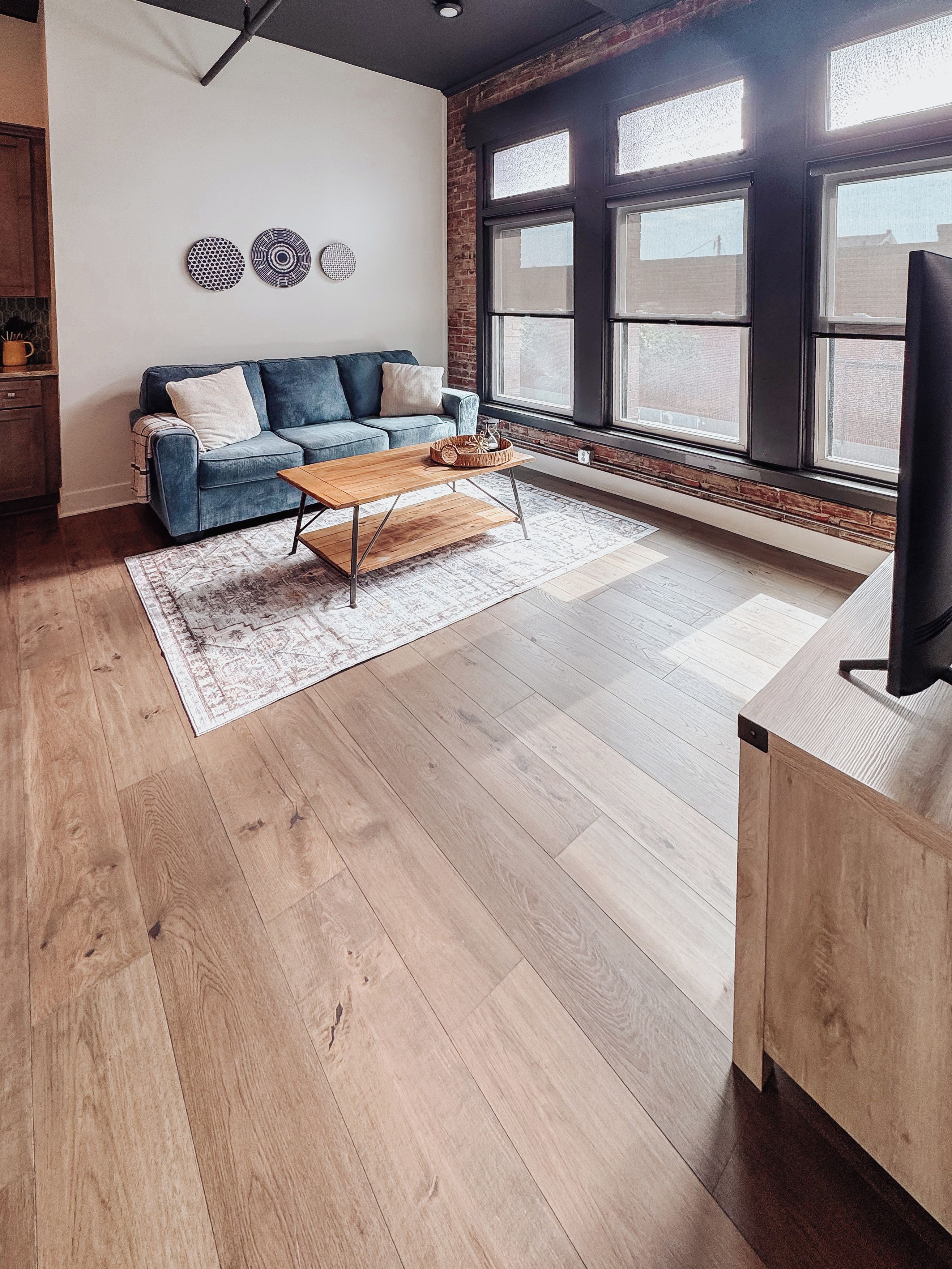 Una sala de estar moderna con sofá, mesa de centro y ventanas grandes.