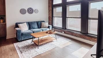 Una sala de estar moderna con sofá, mesa de centro y ventanas grandes.