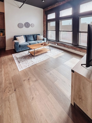 Una sala de estar moderna con sofá, mesa de centro y ventanas grandes.