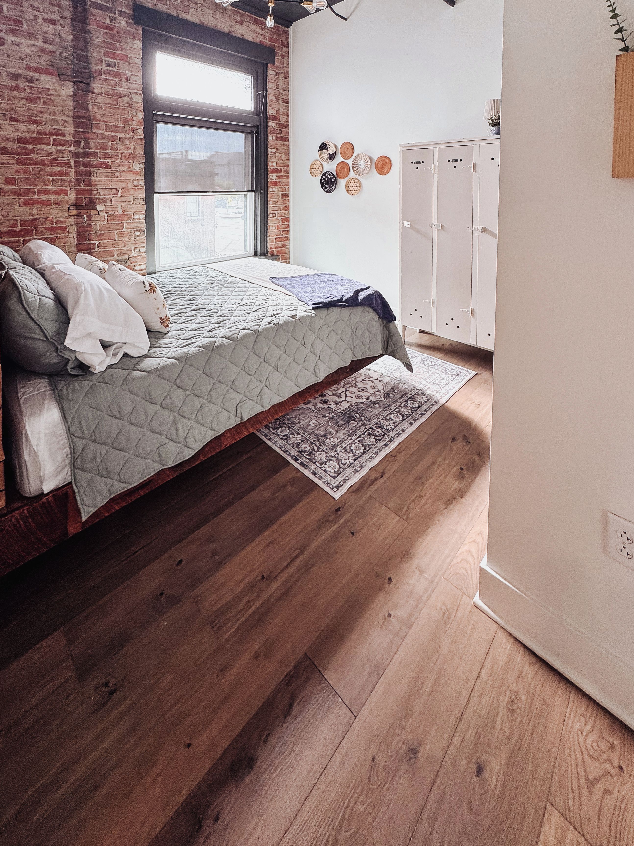 Un dormitorio con cama, suelo de madera, ventana y armario.