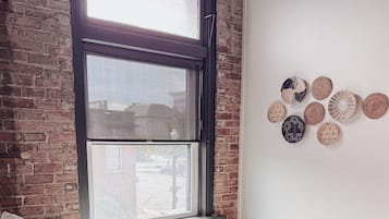 A room with a bed, a window with blinds, a brick wall, and a wall with circular wall hangings.