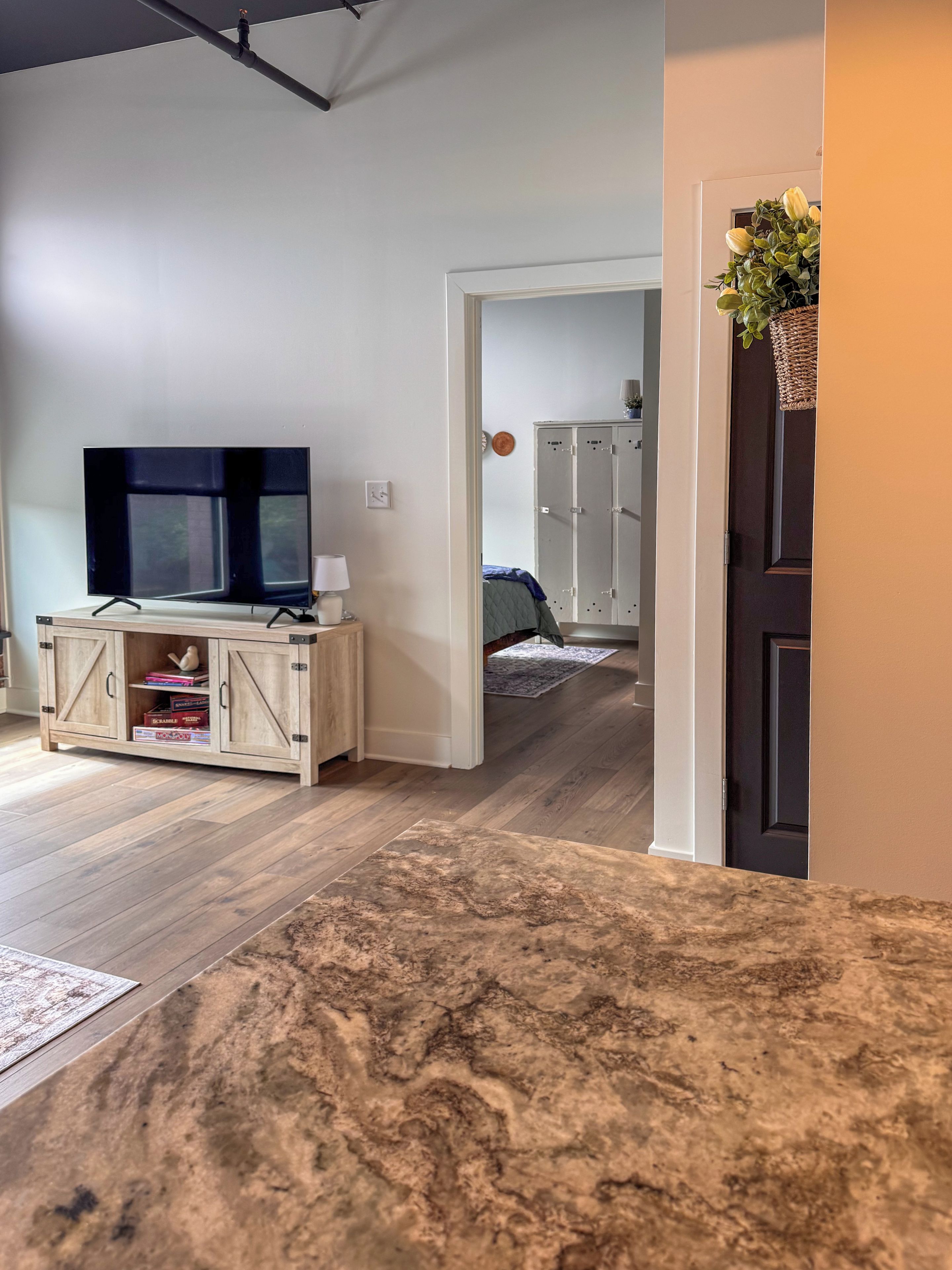 Een woonkamer met een televisie, een houten kast en een gang naar een slaapkamer.