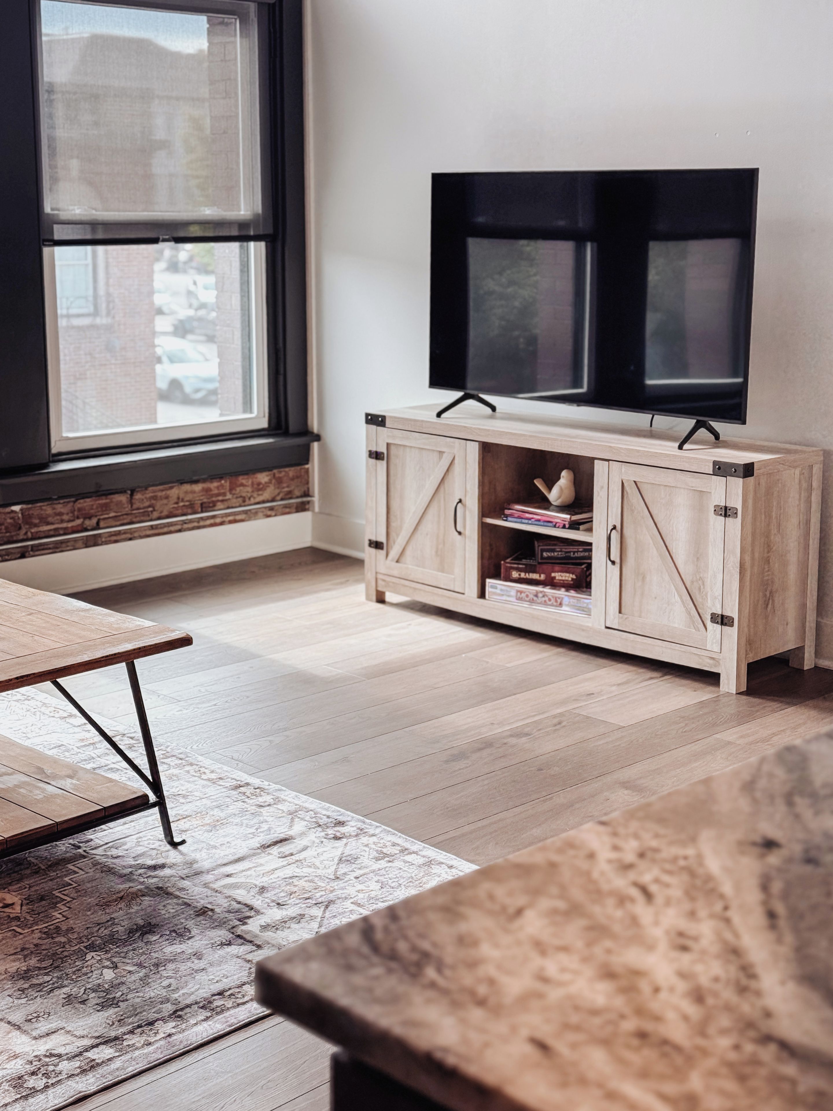 Una stanza con un armadio in legno, una televisione, una finestra e un tappeto decorato.