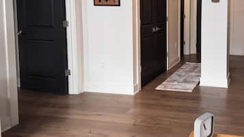 A hallway with wooden flooring, black doors, a wall-mounted map, and a clock.
