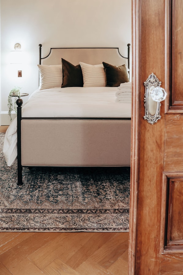 Une chambre à coucher avec un lit, une table de chevet, une lampe et une porte.