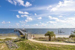 A pier extending into a calm body of water with a clear sky and a distant city skyline. - BYO Boat! 2BR Waterfront Condo (Pensacola)