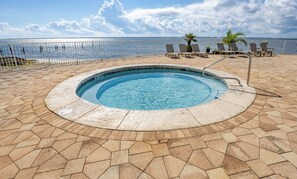 A swimming pool with a surrounding deck, lounge chairs, and a view of the sea. - BYO Boat! 2BR Waterfront Condo (Pensacola)