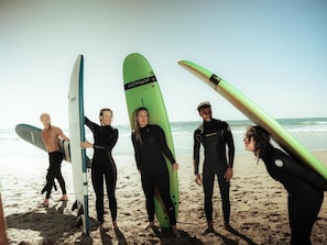 A group of people on a beach holding surfboards. - Agachill Surf House (Aourir)