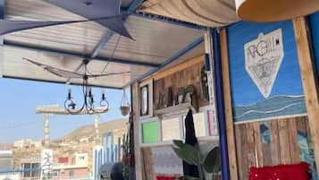 Un espacio exterior acogedor con mesa, sillas y una lámpara colgante.