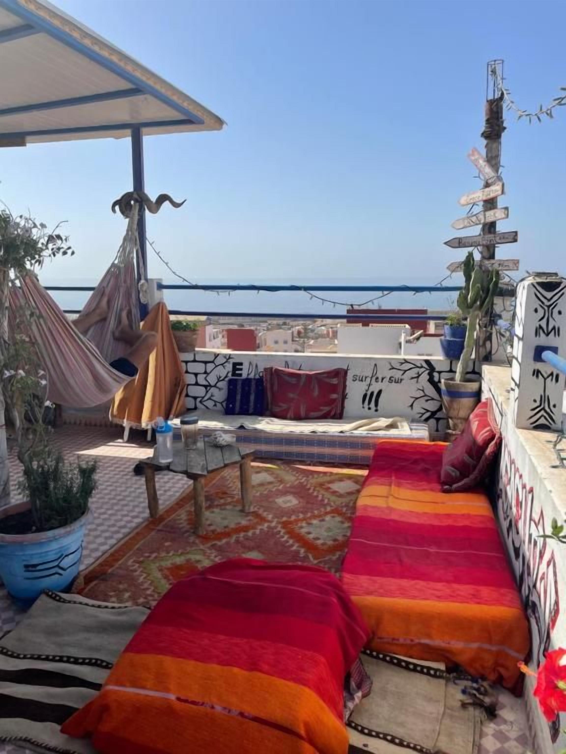 A rooftop terrace with a hammock, a sofa, and a view of the sea.