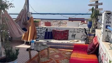 A rooftop terrace with a hammock, a sofa, and a view of the sea.
