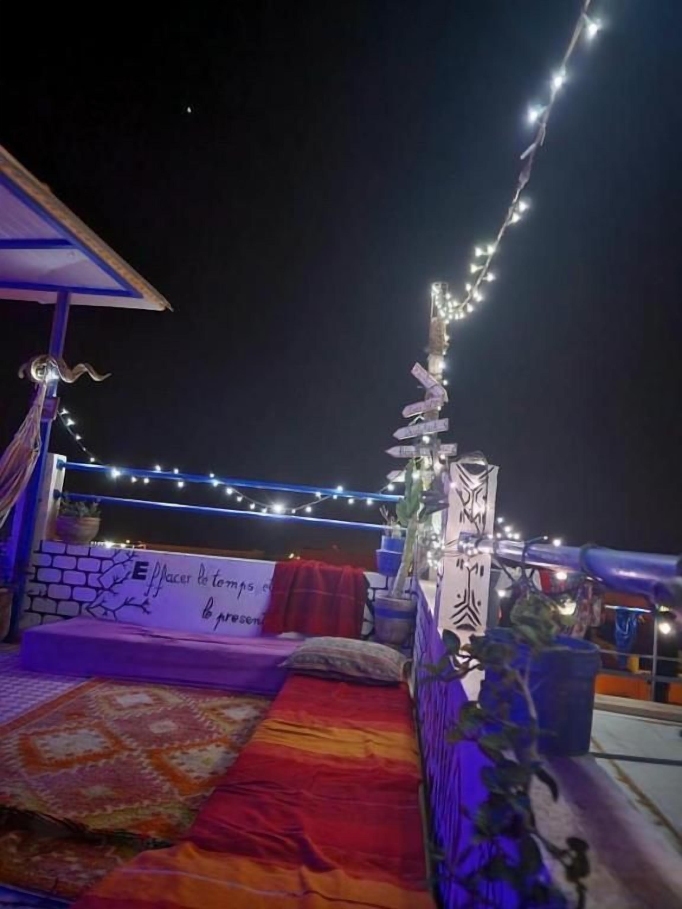 Un espacio al aire libre con asientos, un sofá, cojines y un tapete estampado.