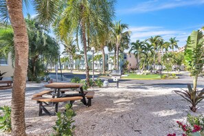 Ein Innenhof mit Palmen, Picknicktischen und einer Straße im Hintergrund.