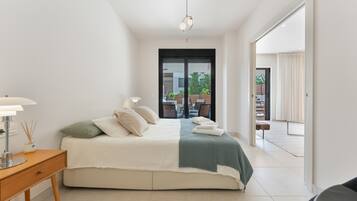 A modern bedroom with a bed, bedside table, lamp, and a view of the outdoors.