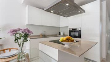A modern kitchen with white cabinetry, a central island, and a dining area with a glass table.