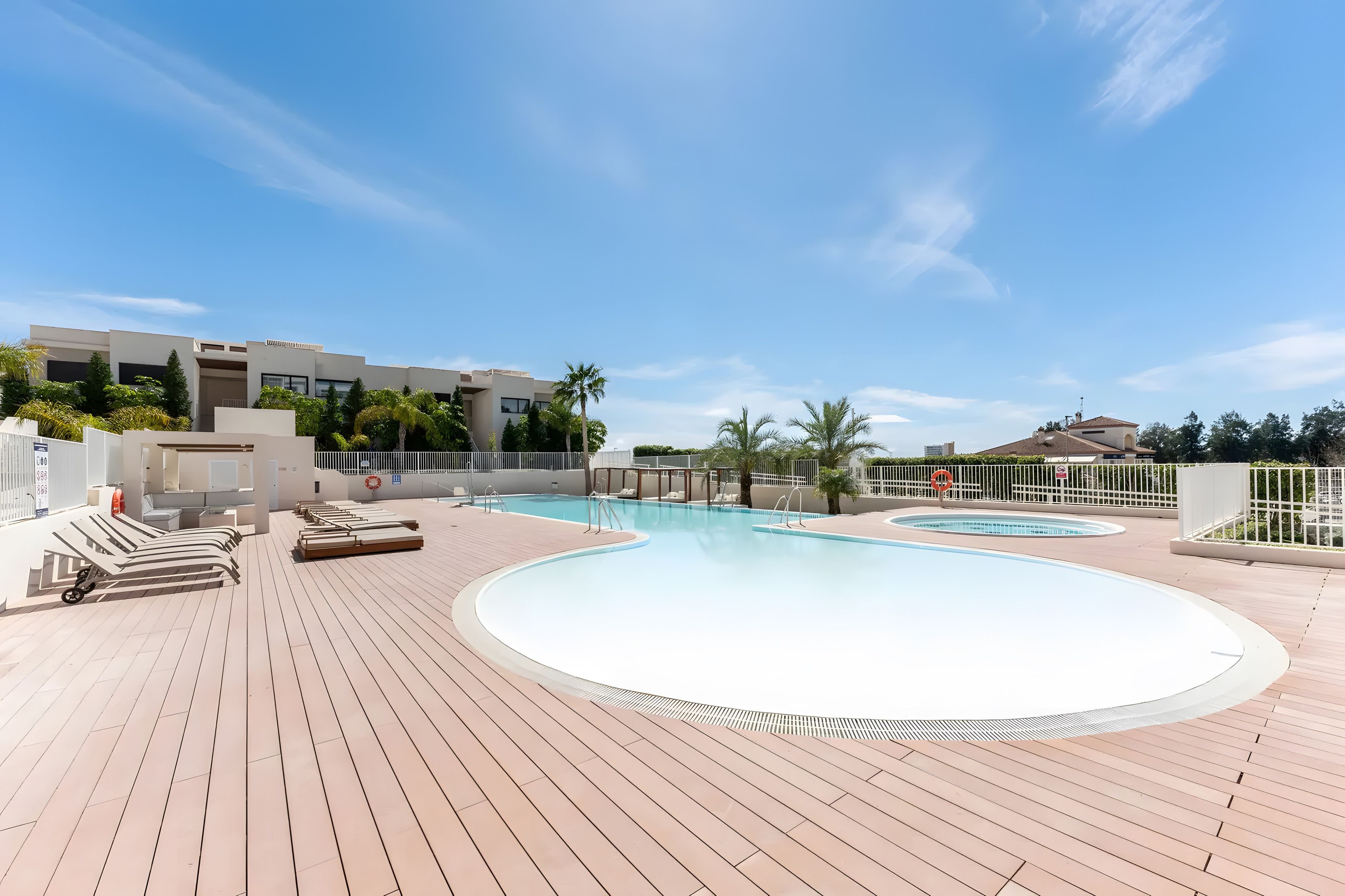 A rooftop pool area with lounge chairs and a clear sky.