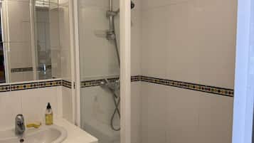 Ein Badezimmer mit einem weißen Waschbecken, einem Spiegel und einer Duschkabine.