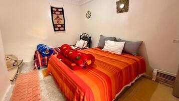 Ein Schlafzimmer mit einem Bett, Kissen, einem Teppich und einer Wanddekoration.