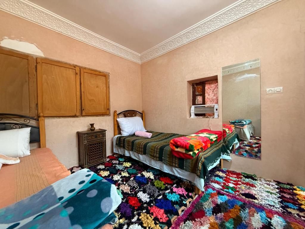 A bedroom with a bed, a nightstand, a dresser, a mirror, and a colorful rug.