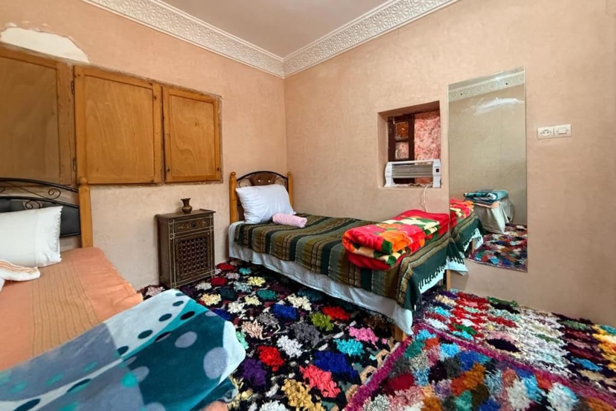 A bedroom with a bed, a nightstand, a dresser, a mirror, and a colorful rug.