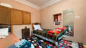 A bedroom with a bed, a nightstand, a dresser, a mirror, and a colorful rug.