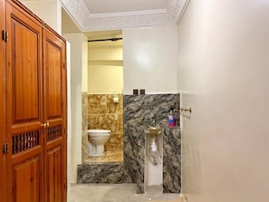 A bathroom with a marble sink, a toilet, and a wooden door.