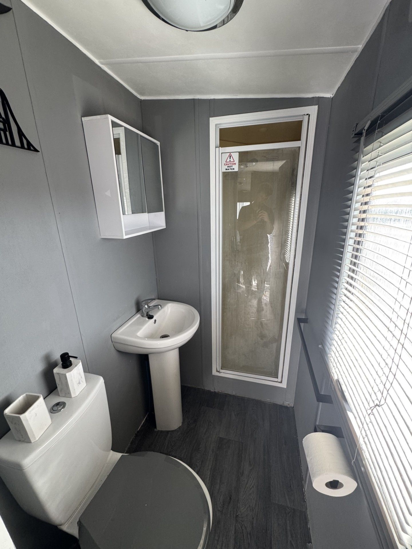 A compact bathroom with a toilet, sink, and shower area.