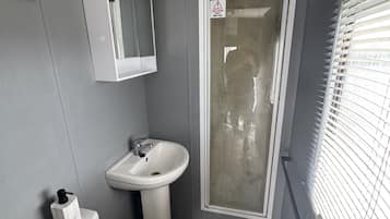 A compact bathroom with a toilet, sink, and shower area.