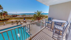 A balcony with a pool, outdoor seating, and a view of the beach. - Destin On The Gulf 204 2 Bedroom Condo (Destin)