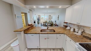 A compact kitchen with a built-in dishwasher, a sink, and a stove. - Destin On The Gulf 204 2 Bedroom Condo (Destin)